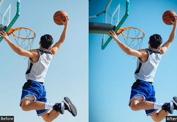 Young basketball player in mid-air dunking the ball towards the hoop during a game, with a clear blue sky background.