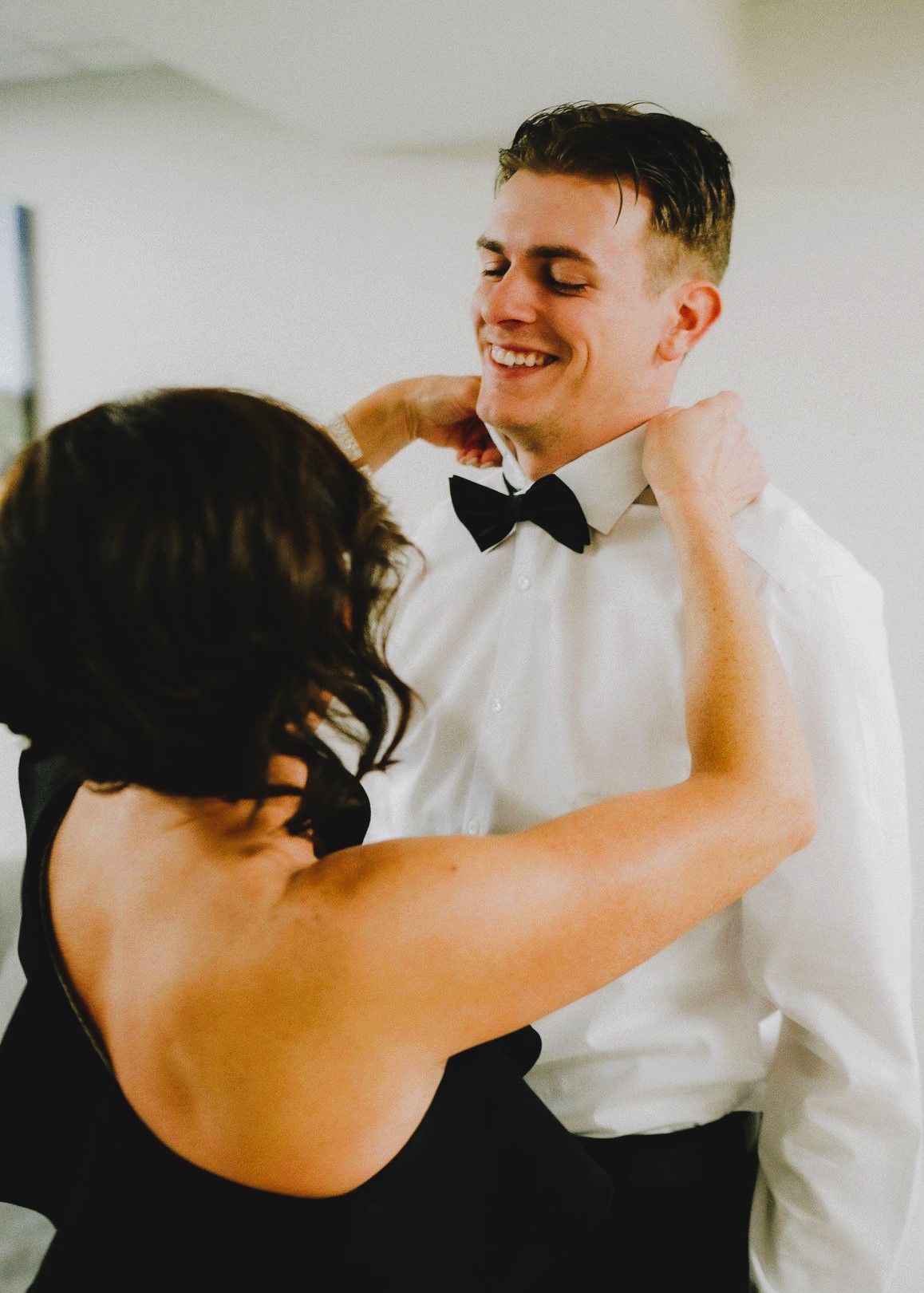 Groom buttoning shirt with groomsmen assisting